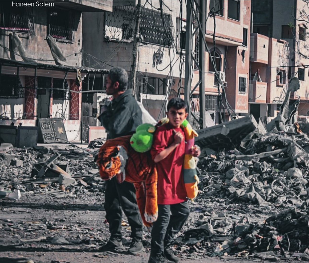 Child emerges from rubble clutching colorful toys after war