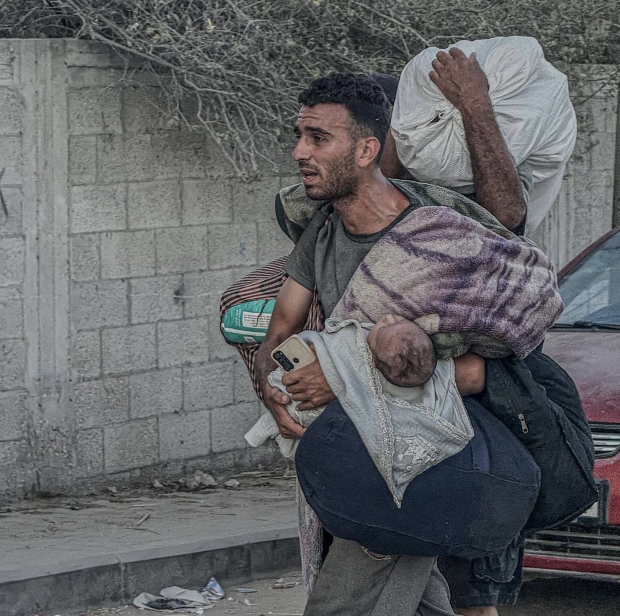 Palestinian Flees Deir Al Balah with Child During Occupation Advance