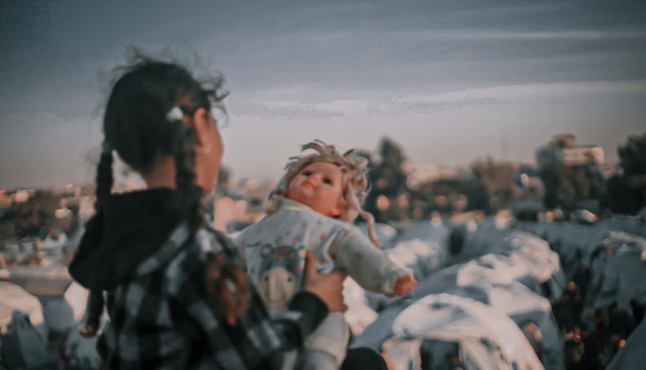 Child in displacement tent holds doll in northern Gaza
