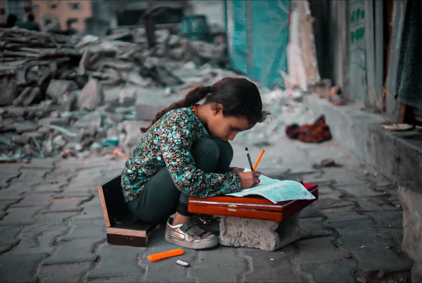 Girl writes in notebook as refuge amid Gaza war ruins