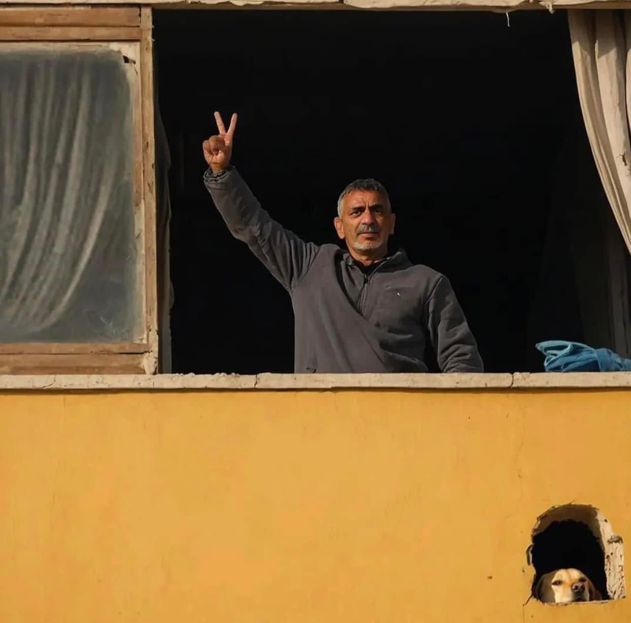 Palestinian raises victory sign amid destroyed Gaza home