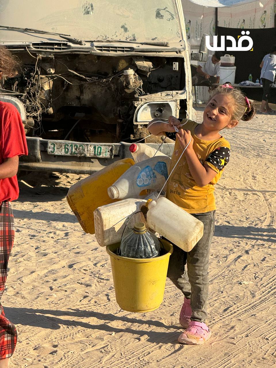 Young Girl Carries Water Through Long Queue in Gaza