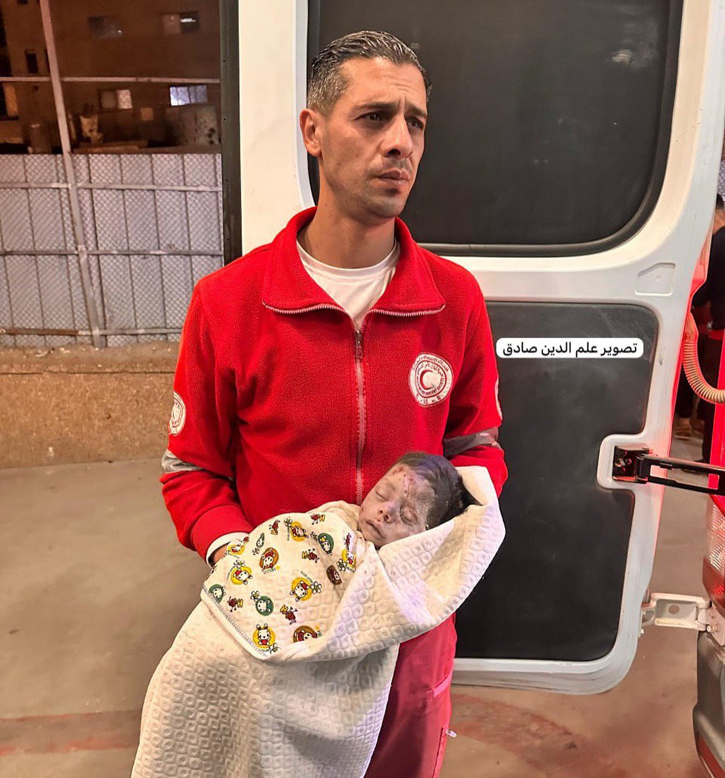 Paramedic carries body of infant killed in Israeli airstrike