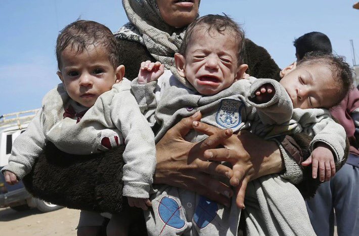 Woman carries three babies fleeing Al-Shifa hospital in Gaza
