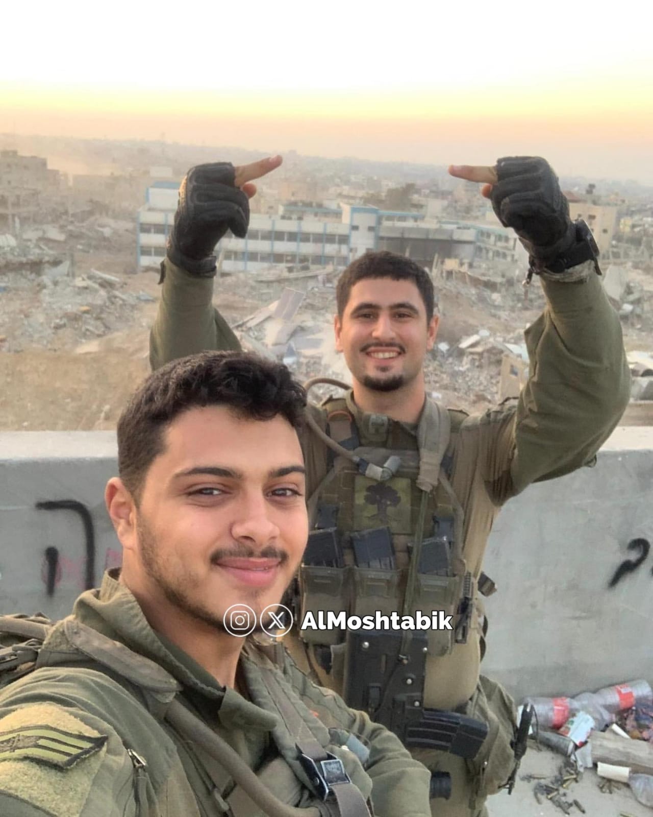 IOF soldiers pose with destroyed UNRWA school and burned house in Gaza