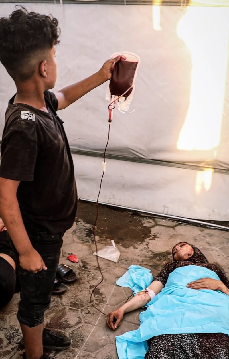 Child holds blood bag for wounded mother after Israeli airstrike