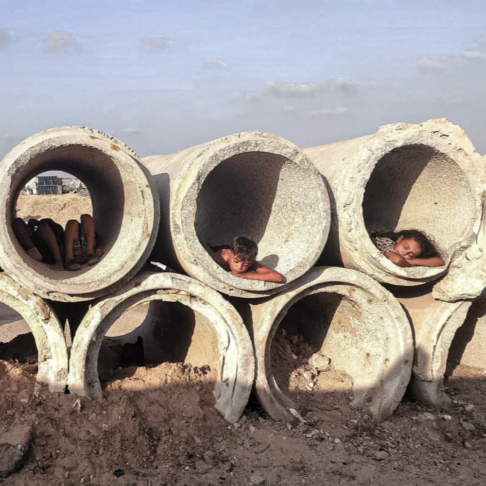Gaza: children flee tent heat into concrete pipes