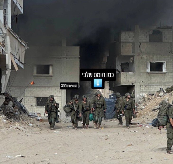 Israeli soldier poses in front of burned homes in Jabalia camp