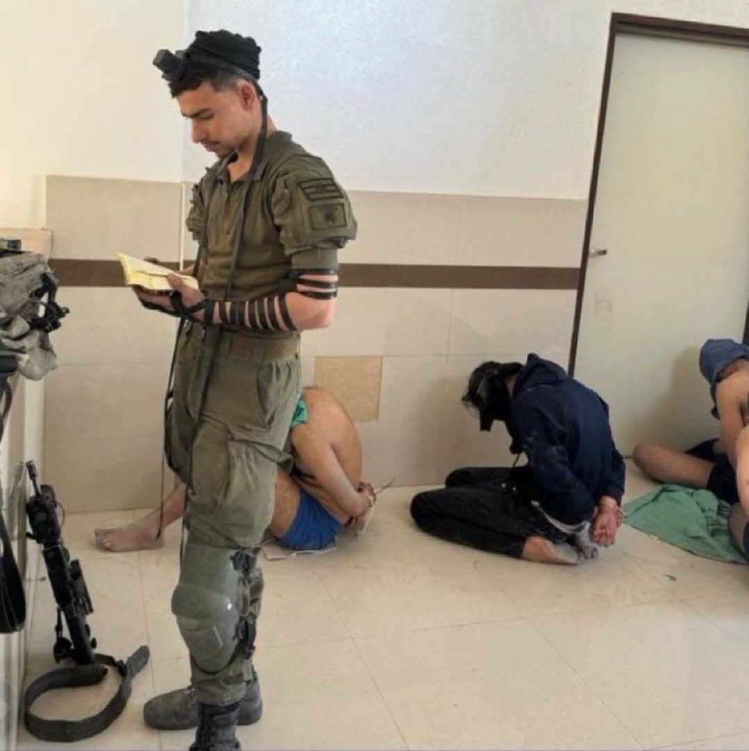 Israeli soldier prays beside bound Palestinians in raided Gaza hospital
