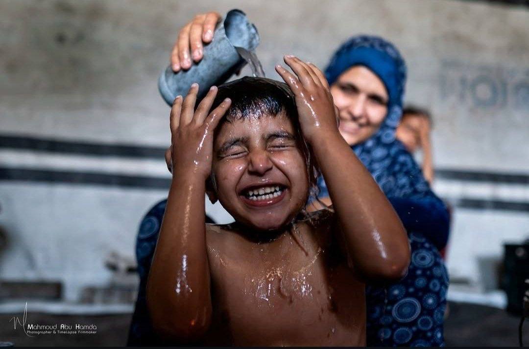 Gaza mother cools children with scarce water in tent amid heat